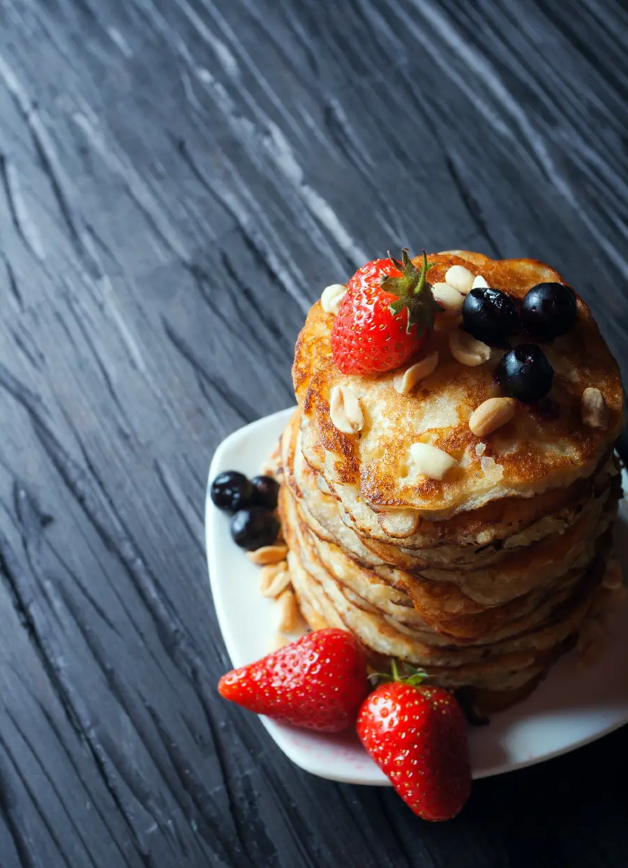 Download free and high-quality photo of pancakes decorated with blueberries and strawberries and peanuts