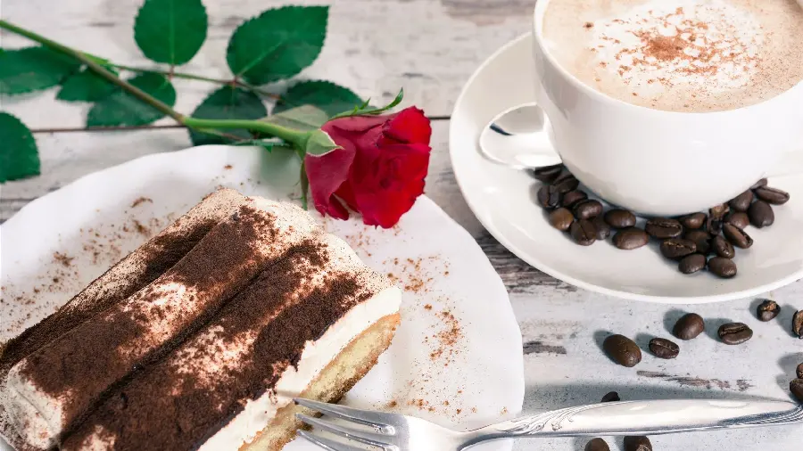 Attractive photo of Delicious chocolate tiramisu with a red rose branch next to it