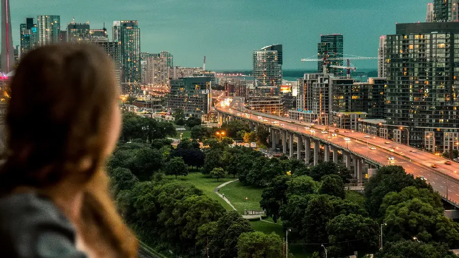 A very interesting picture of a beautiful woman by the window of a big city