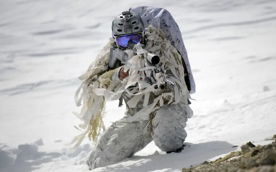 Photo of a soldier with a gun in his hand in white camouflaged in the snow