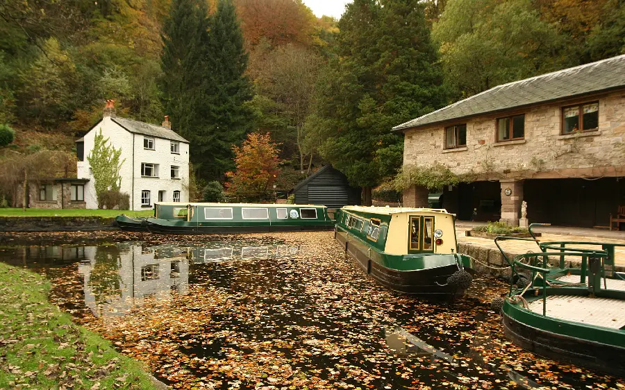 A beautiful and old picture of a cottage and kayaks on the water