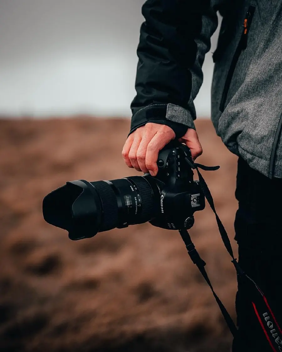 Download wallpaper of a boy holding a camera on a laptop