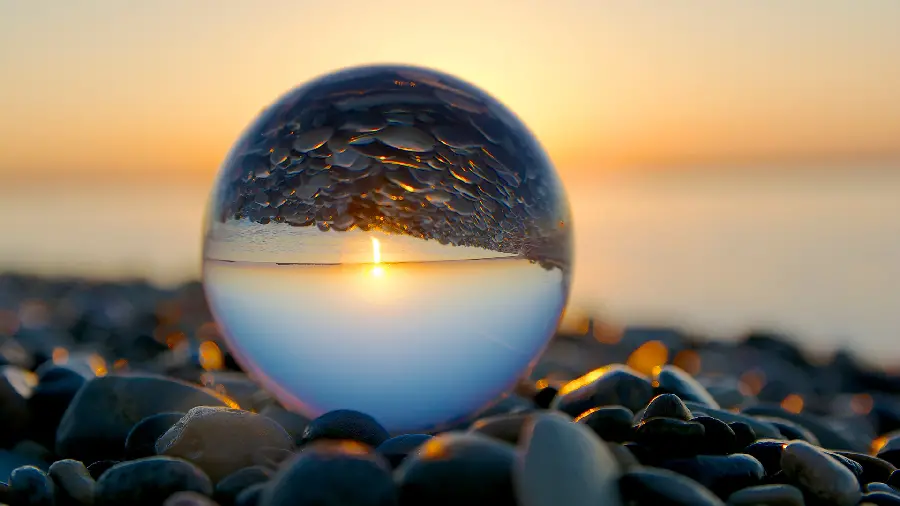 A spectacular portrait of the sunset over the sea and its reflection in a glass ball in 4K quality