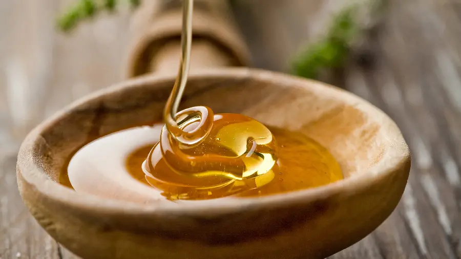 A charming and close-up stock image of a transparent and golden honey syrup 