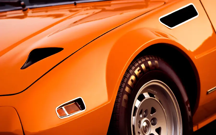 Close-up of an orange car with stylish silver rims
