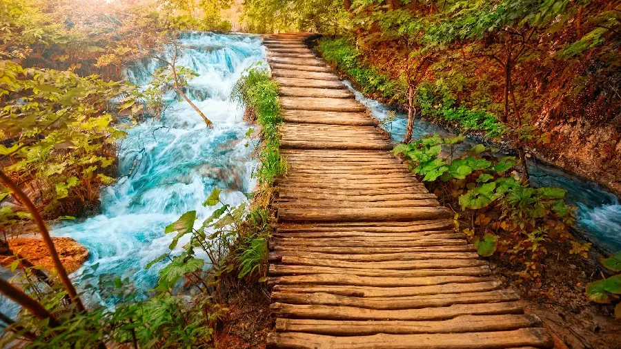 A pleasant photo of a wooden bridge on a river full of water and excitement