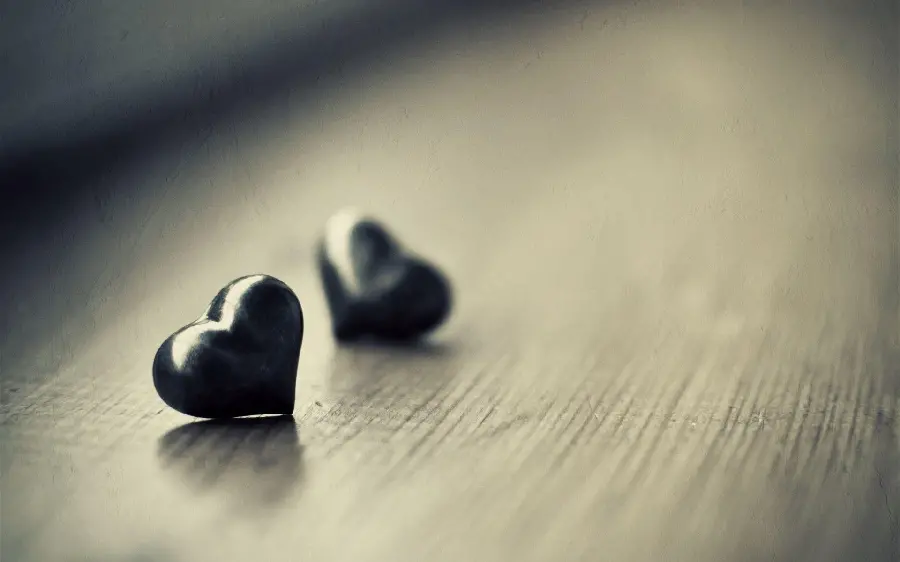 Love Profile and Story Photo of Two Matte Black Hearts on a Wooden Table