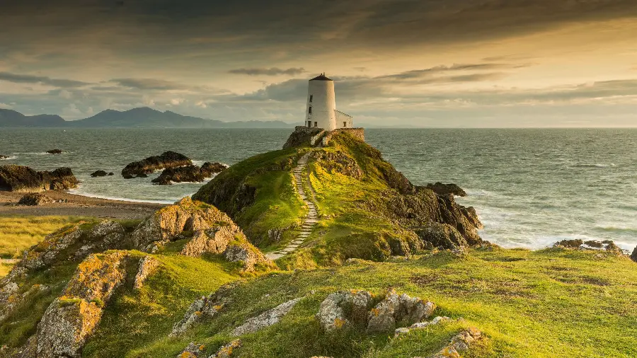 Photo of old lighthouse on large grassy hills on the beach