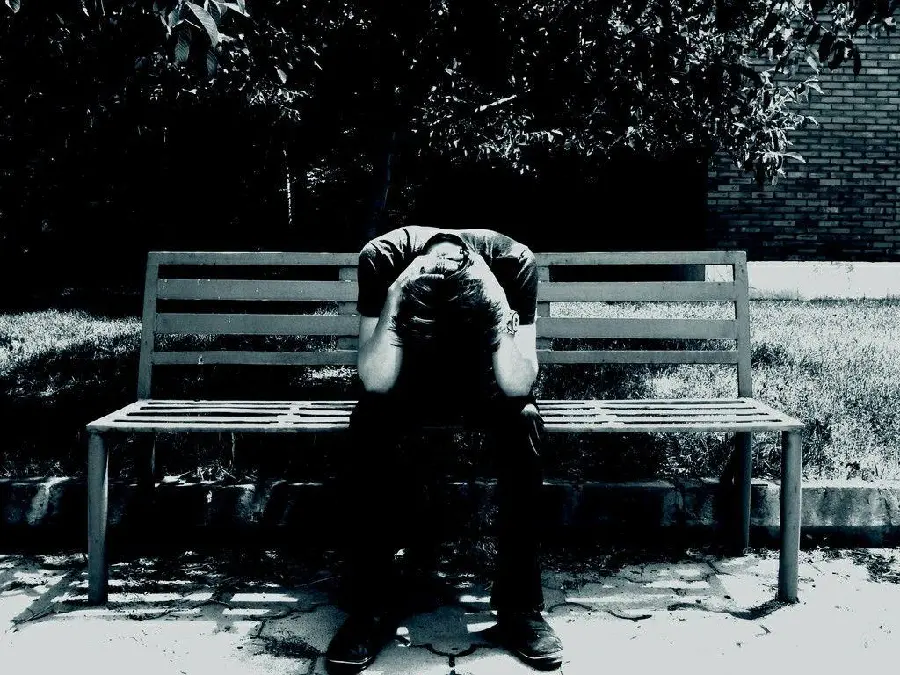 Special background of a sad boy sitting alone on a park bench