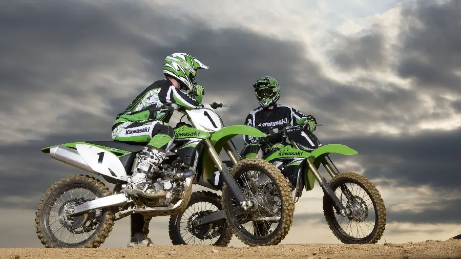 Background image of two motocross riders talking on Kawasaki motocross bikes on a rainy day