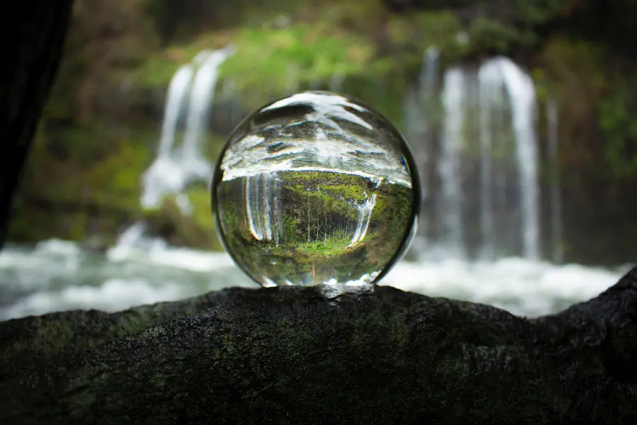 The most beautiful edited photo of a transparent crystal ball with a natural waterfall background 