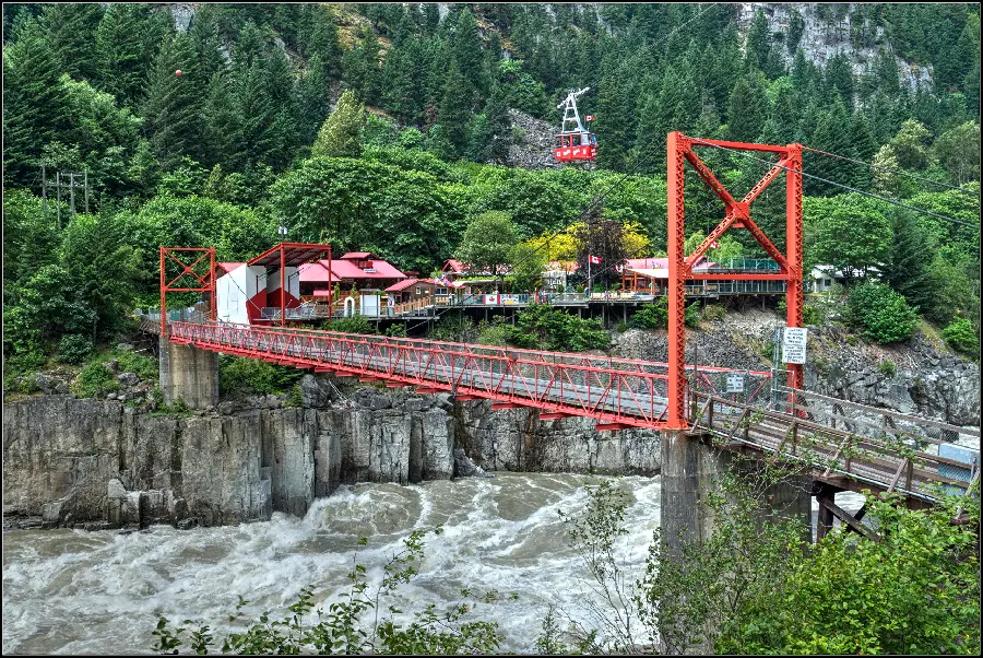 Awesome and exciting photo of a suspension bridge over a raging lake 