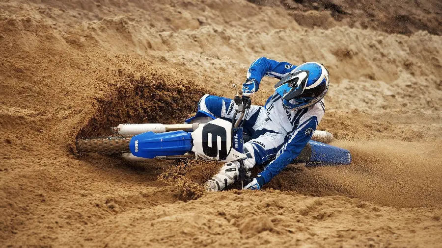 Wallpaper of a cool and exciting scene of a motorcycle rider getting caught in the dirt of a Yamaha motorcycle race