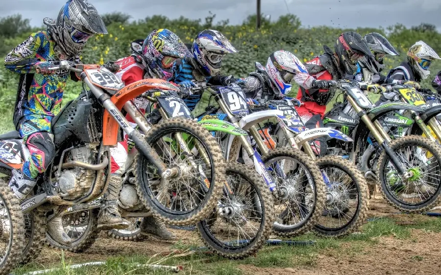 Profile photo of waiting motorcyclists at the starting line of a motocross track race