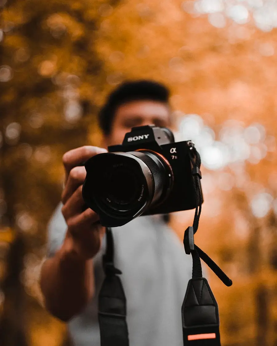 Download a boy's profile photo of a man holding a camera with an autumn background