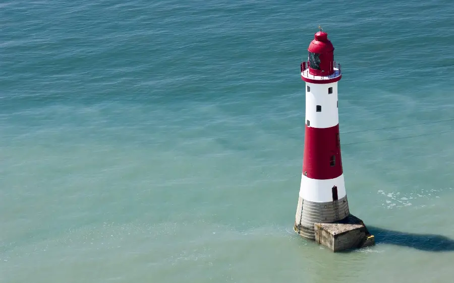 A photo of a white and red lighthouse with a view of the open sea