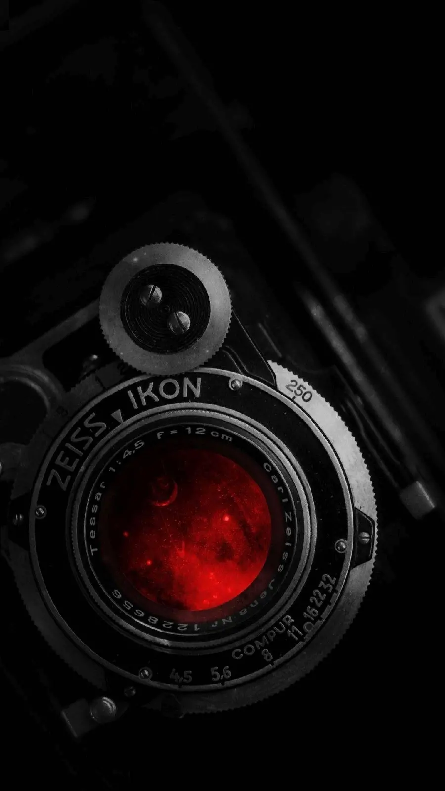 Dark and creepy image of a camera with a red lens and a black background