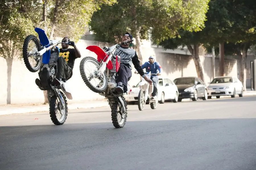 Photo of two motocross riders unicycling on a street corner