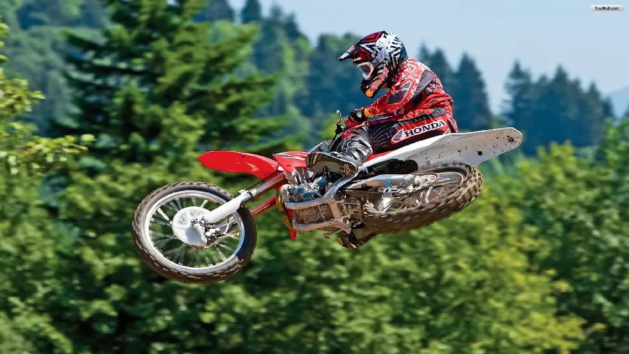 Image of a spectacular jump as high as cypress and pine trees with a trail motorcycle