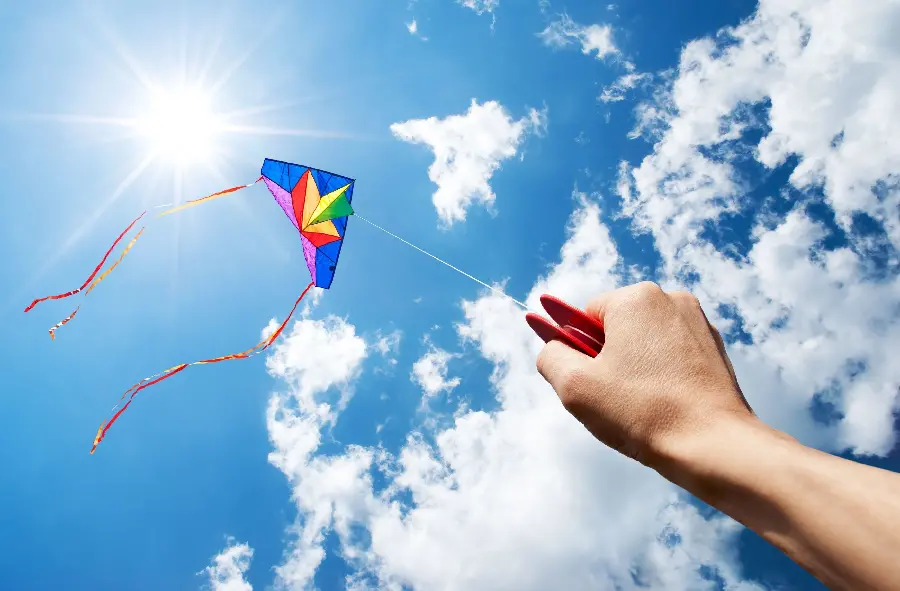Download photo of a rainbow kite flying in a clear and sunny sky