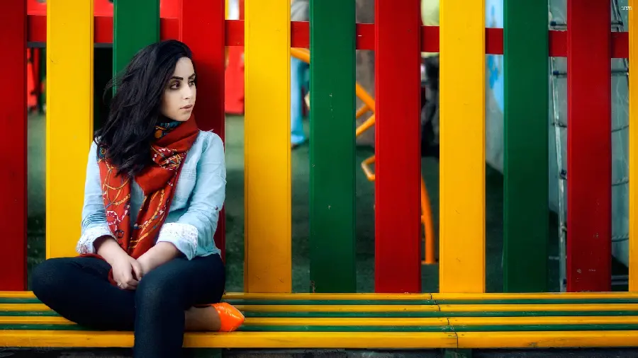Girl's profile photo of a girl sitting next to colorful wooden fences