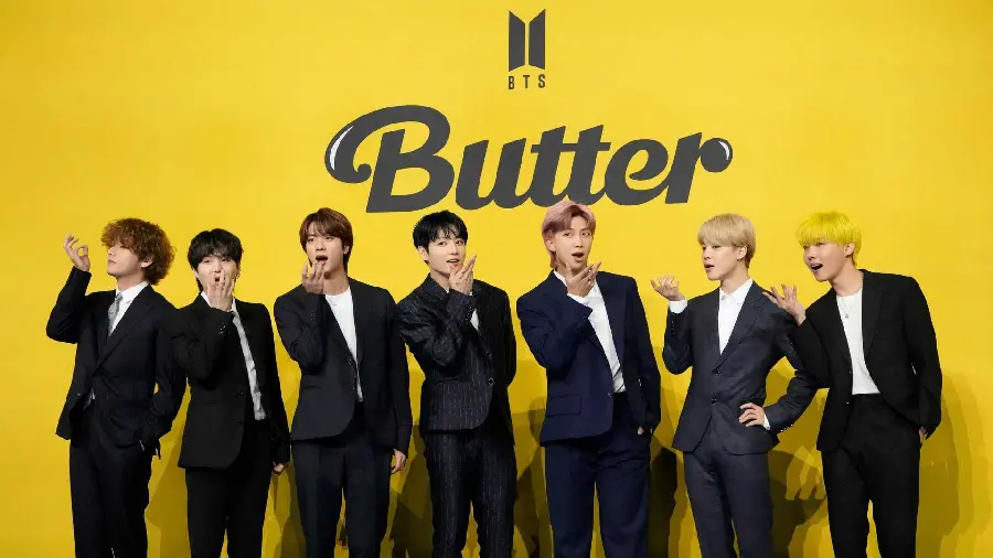 Photo of BTS members with the background of the music video poster Butter