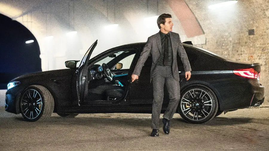 Wallpaper of Tom Cruise next to a luxury BMW car