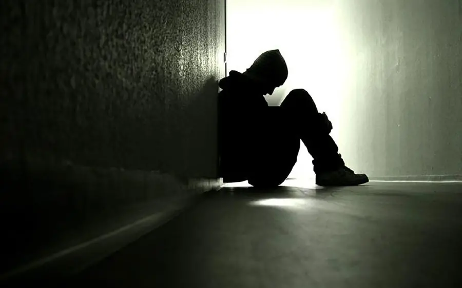 Sad boy alone in the corner of the wall kneeling in the arms for a profile picture