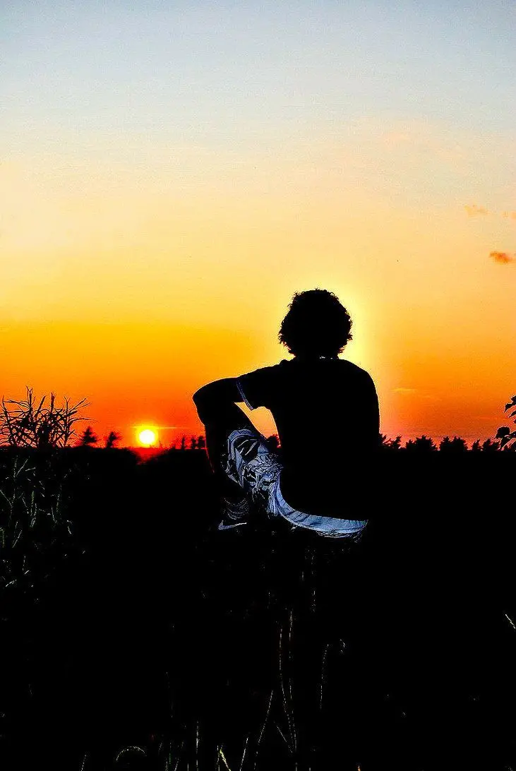 Lonely boy and sunrise background with orange and black colors