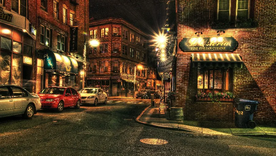 High quality photo of the Italian street at night and cars parked next to the cafe