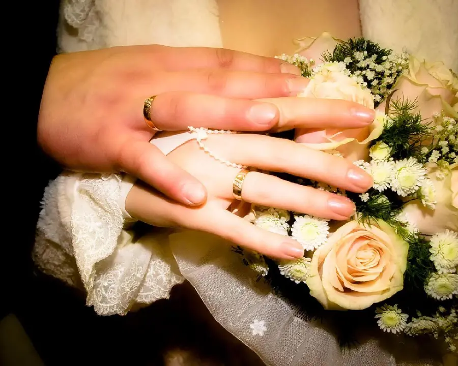 Picture of bride and groom hands next to flower