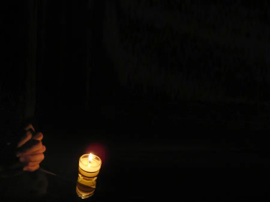 Black background with praying hands and candles for writing condolences and sad feelings