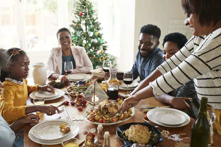 Photo of a happy family eating and serving dinner