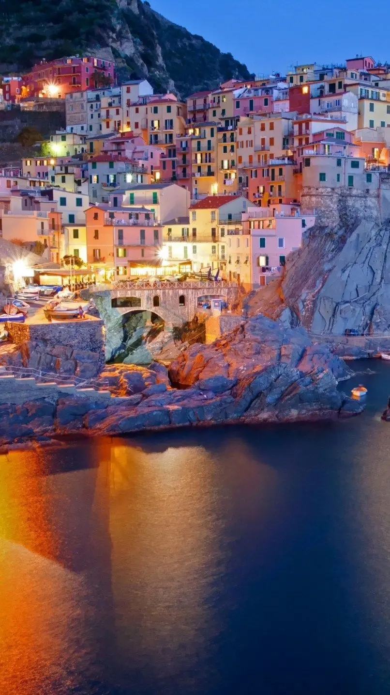 Photo of the city of Italy at night on the rocky coast