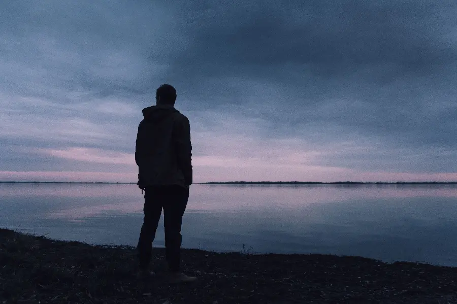 Wallpaper of a lonely and sad boy by the lake and dark weather