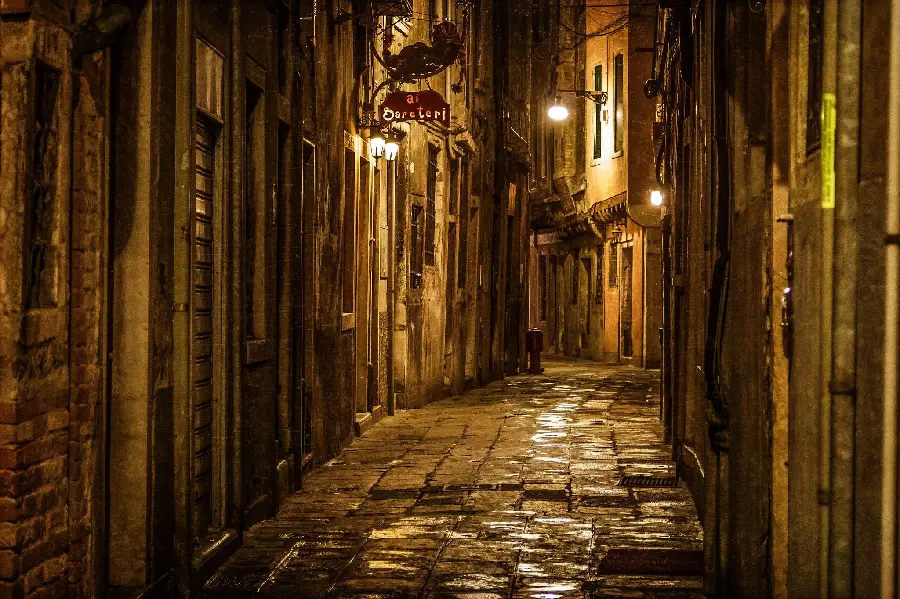 Image of narrow cobblestone streets in Italy at night with bright lights