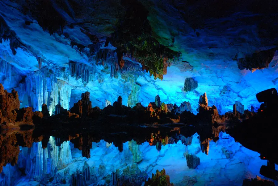 Image of a large natural cave with blue crystals in the reflection of the lake