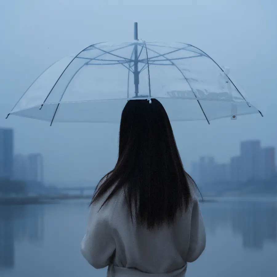 Image of a transparent, glass umbrella made of talc in the rain in the hands of a girl