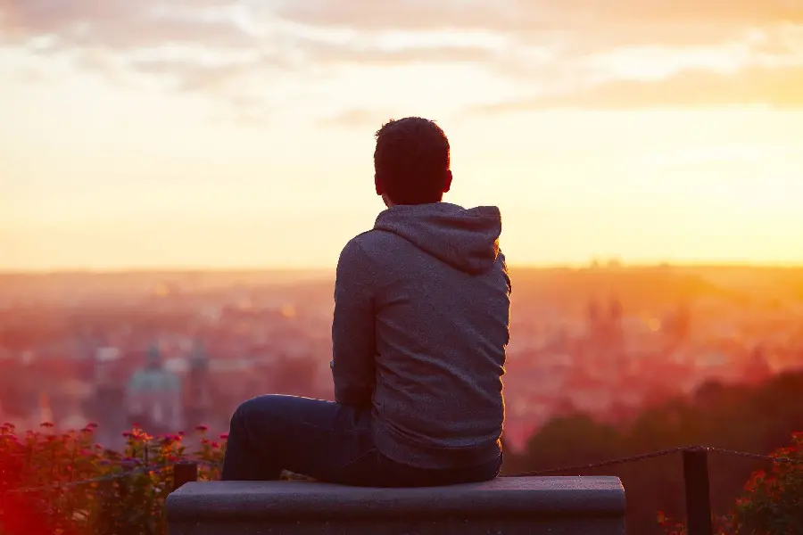 Download your boy's profile picture sitting alone on a bench in the sunset of the city, sad and upset