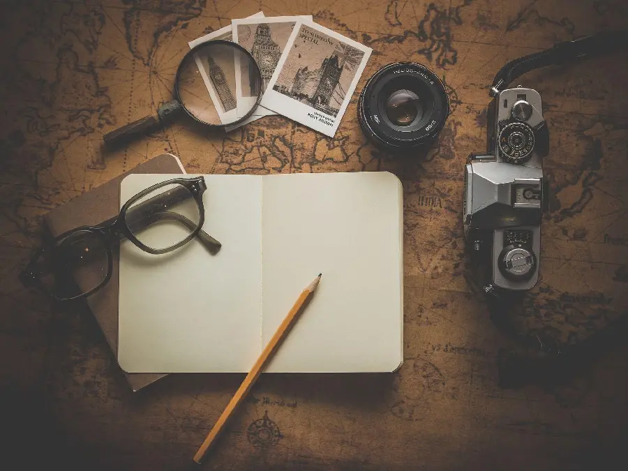 Photo of white book and pen for writing text next to old tools