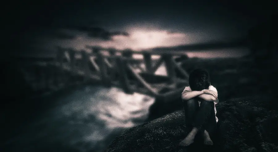 Black and sad photo of a lonely and sad boy kneeling and crying