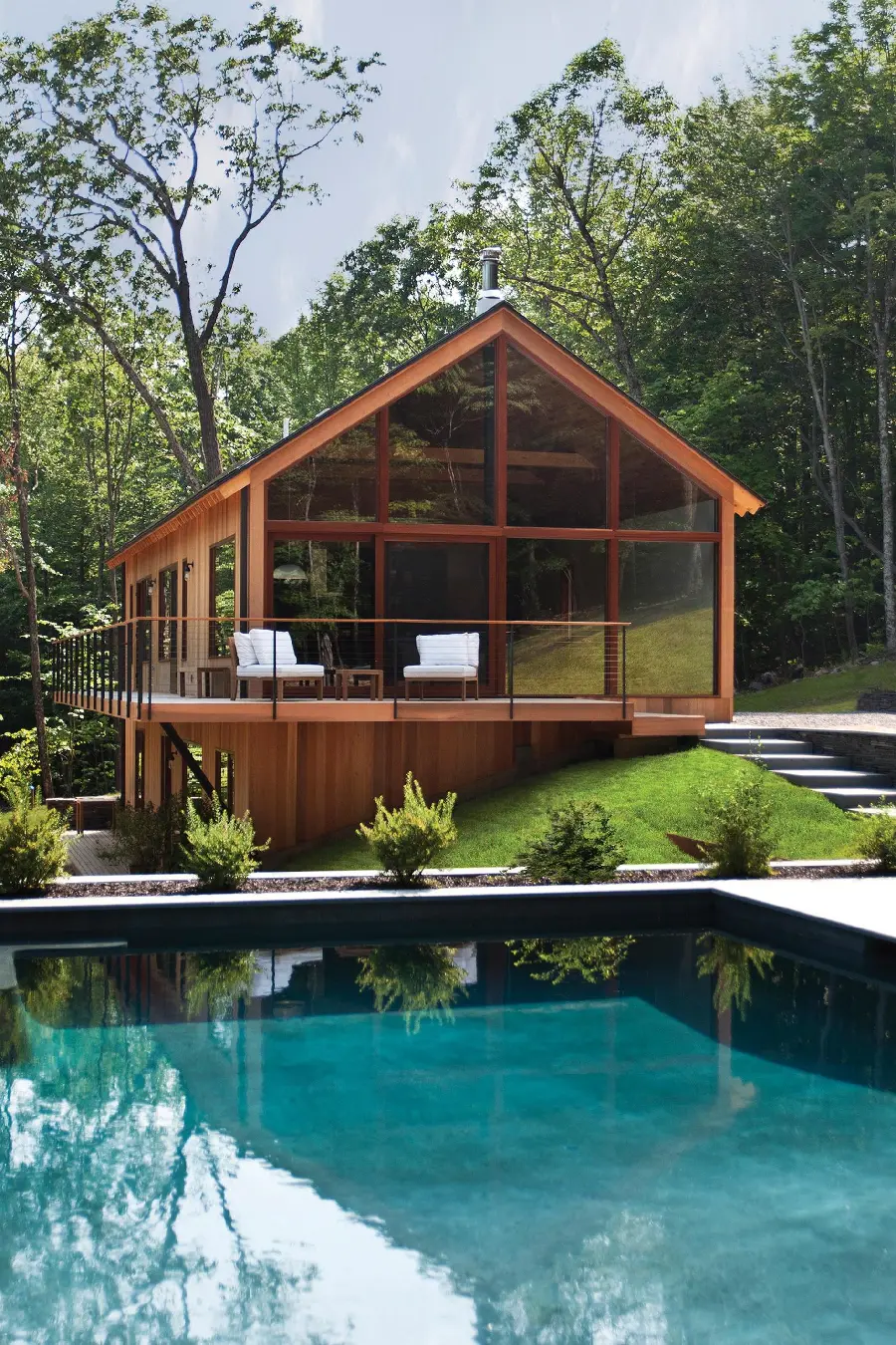 Image of glass cottage combined with wood gable roof by the pool