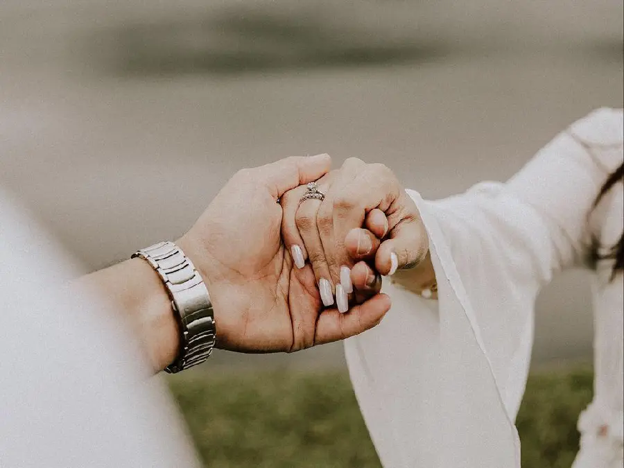 Example of a groom taking a photo of the bride's hand with wedding rings for a profile photo