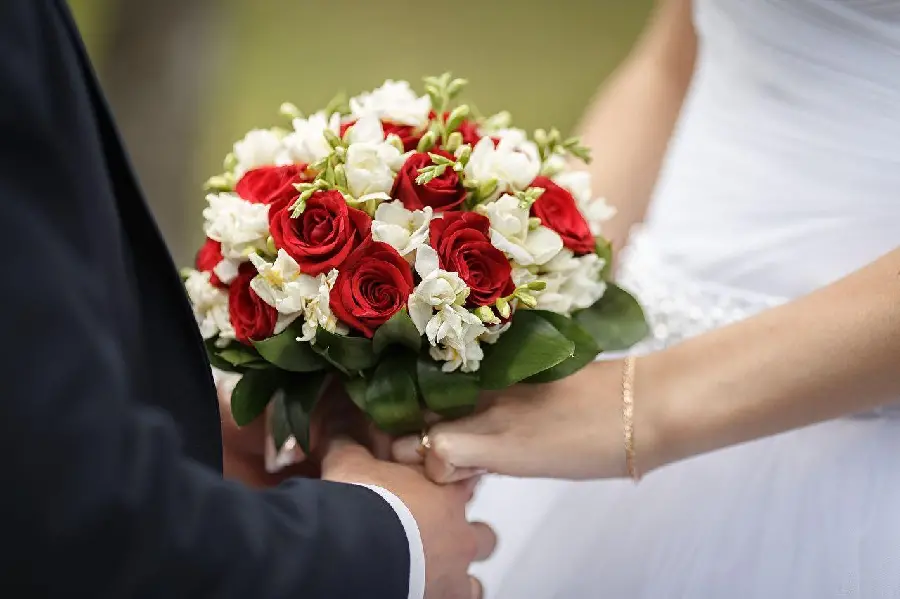 Photo of a bouquet of flowers and hands of the bride and groom for a profile